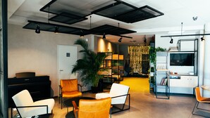 A modern living room with a piano, seating, and a bookshelf. - ibis Valladolid (Valladolid)
