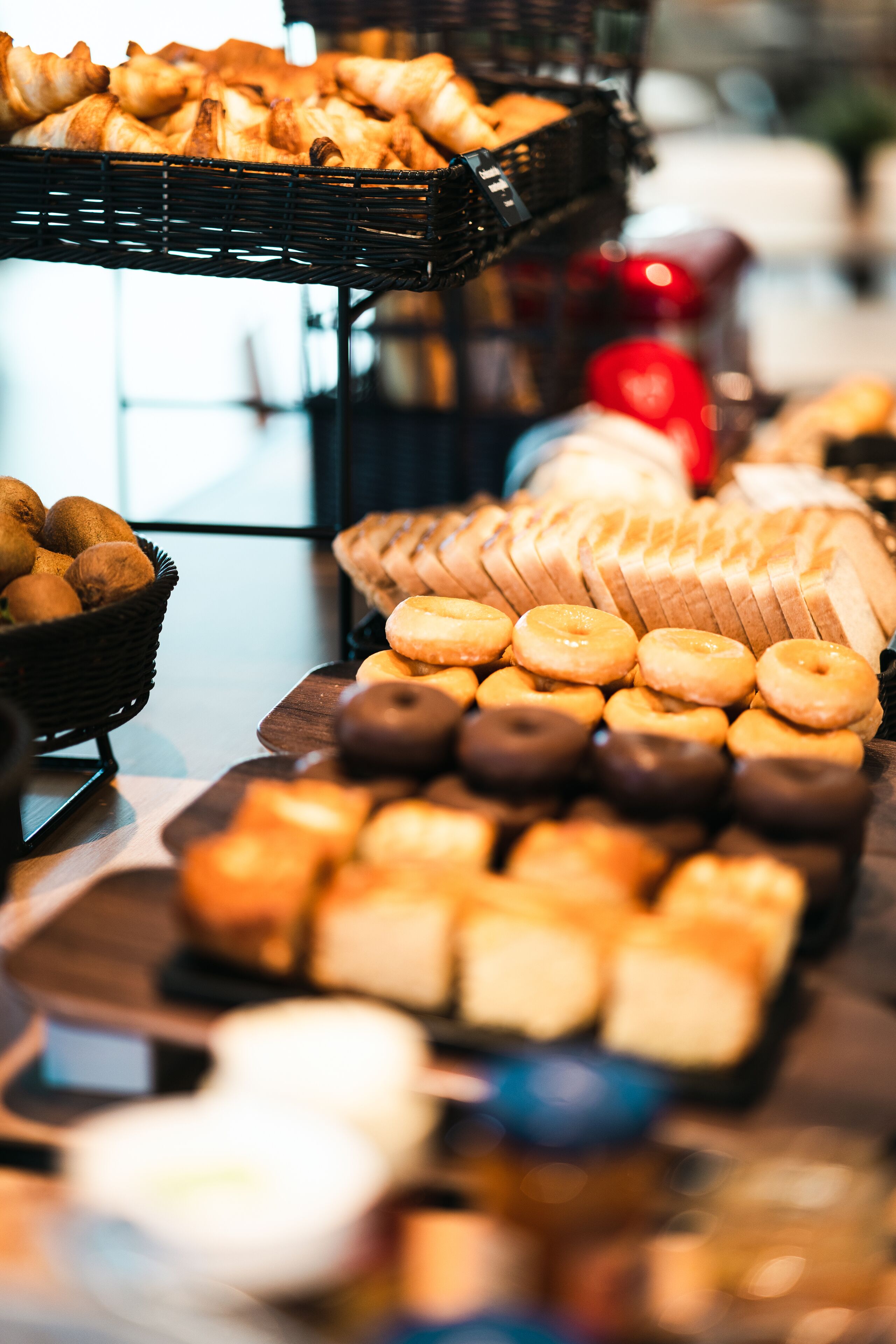 Diverse gebakjes en broodjes op een tafel, waaronder donuts, gebak en brood.