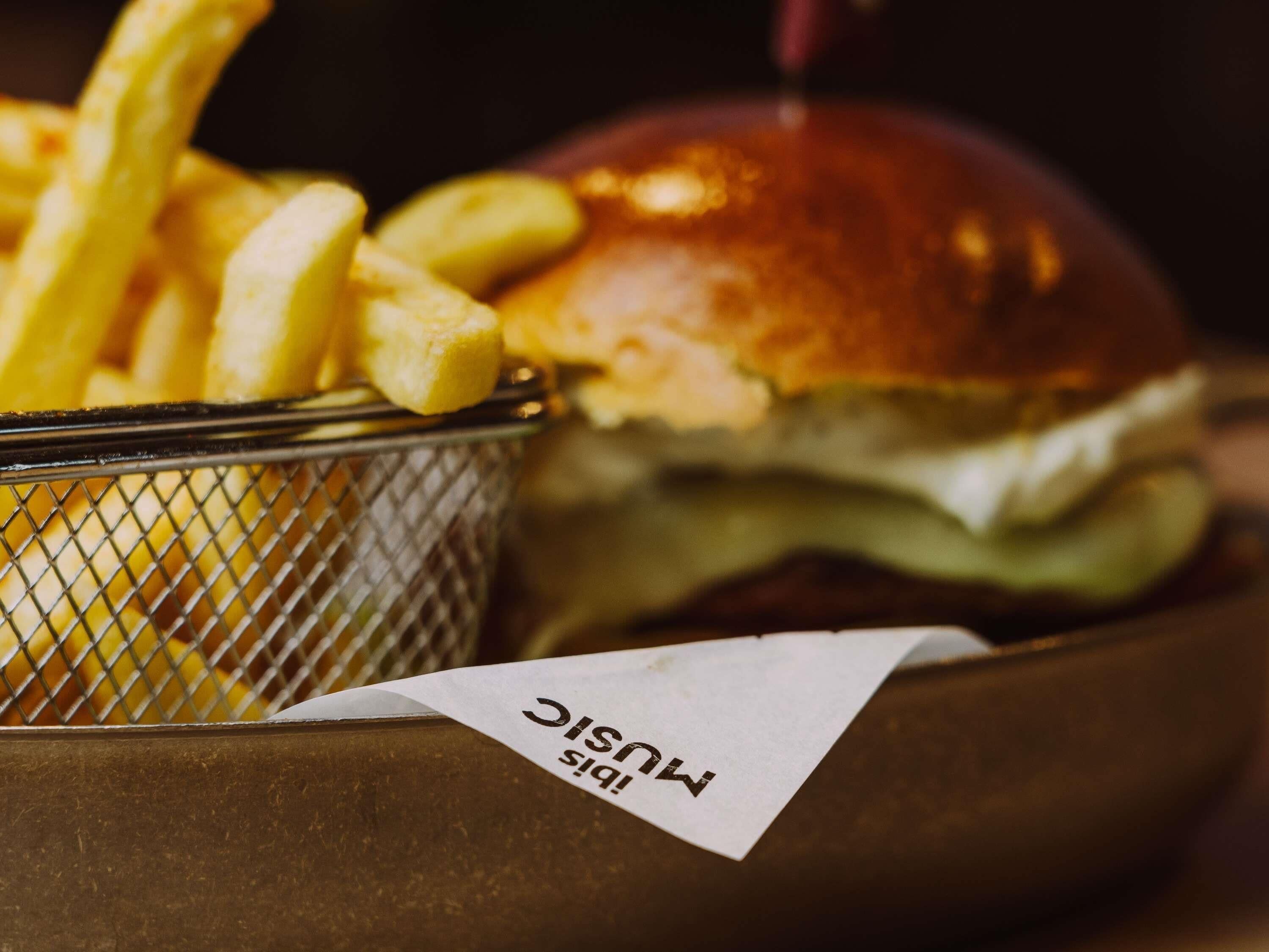 A basket containing French fries and a burger with a bun, placed on a table.