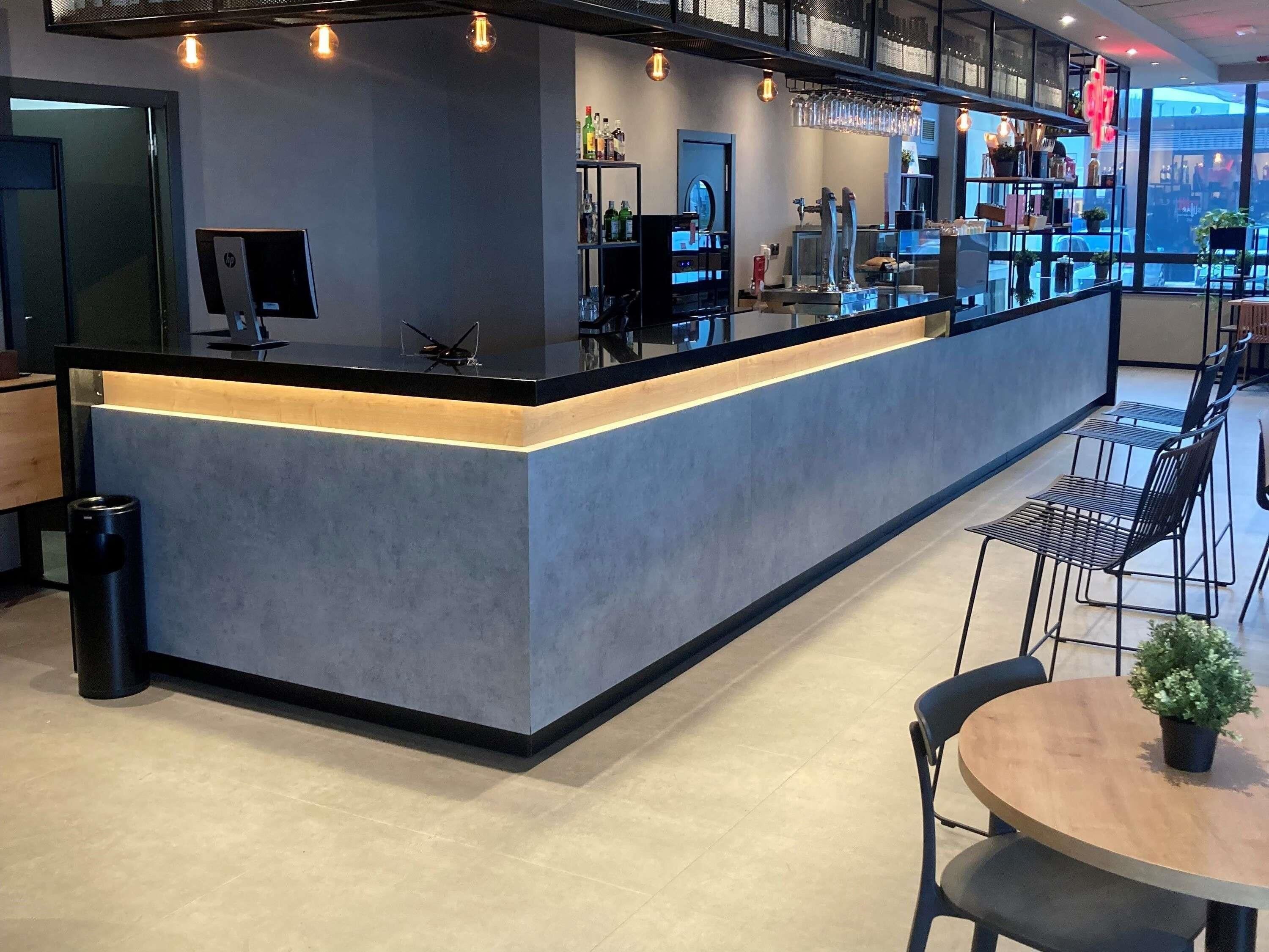 A modern bar area with a counter, seating, and a view of the outside.
