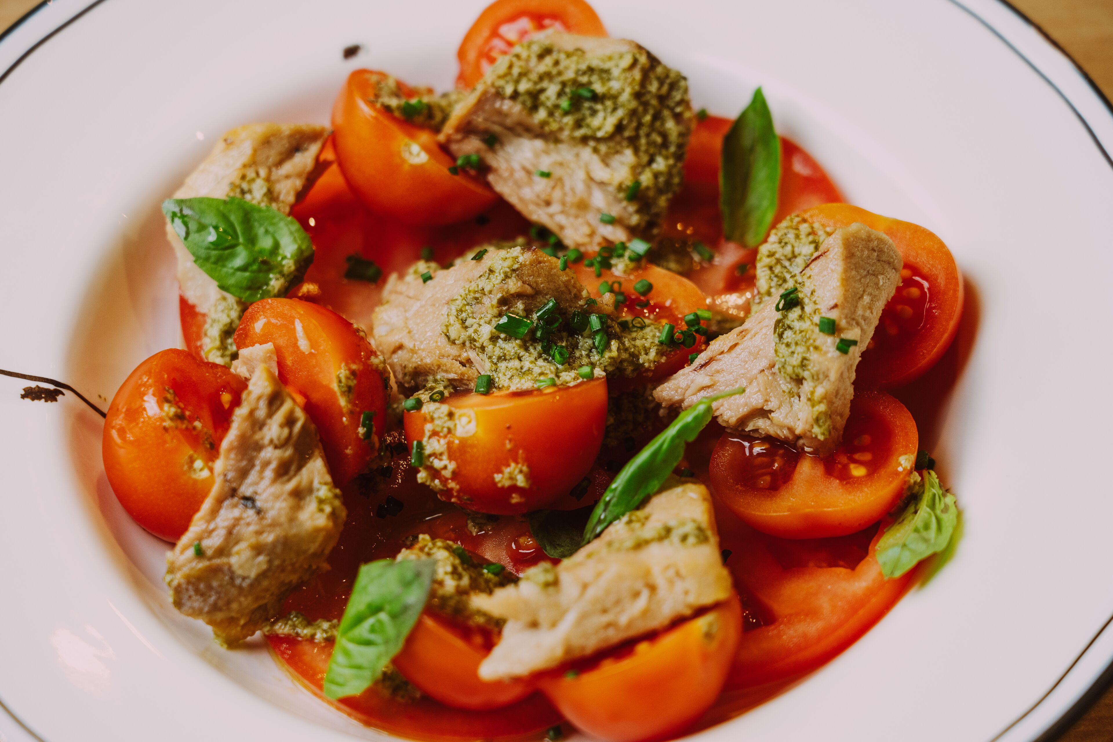 A dish with meat, tomatoes, and basil.