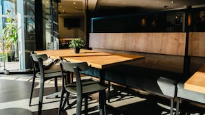 A modern dining area with a wooden table and chairs, a potted plant, and a partition wall. - ibis Valladolid (Valladolid)