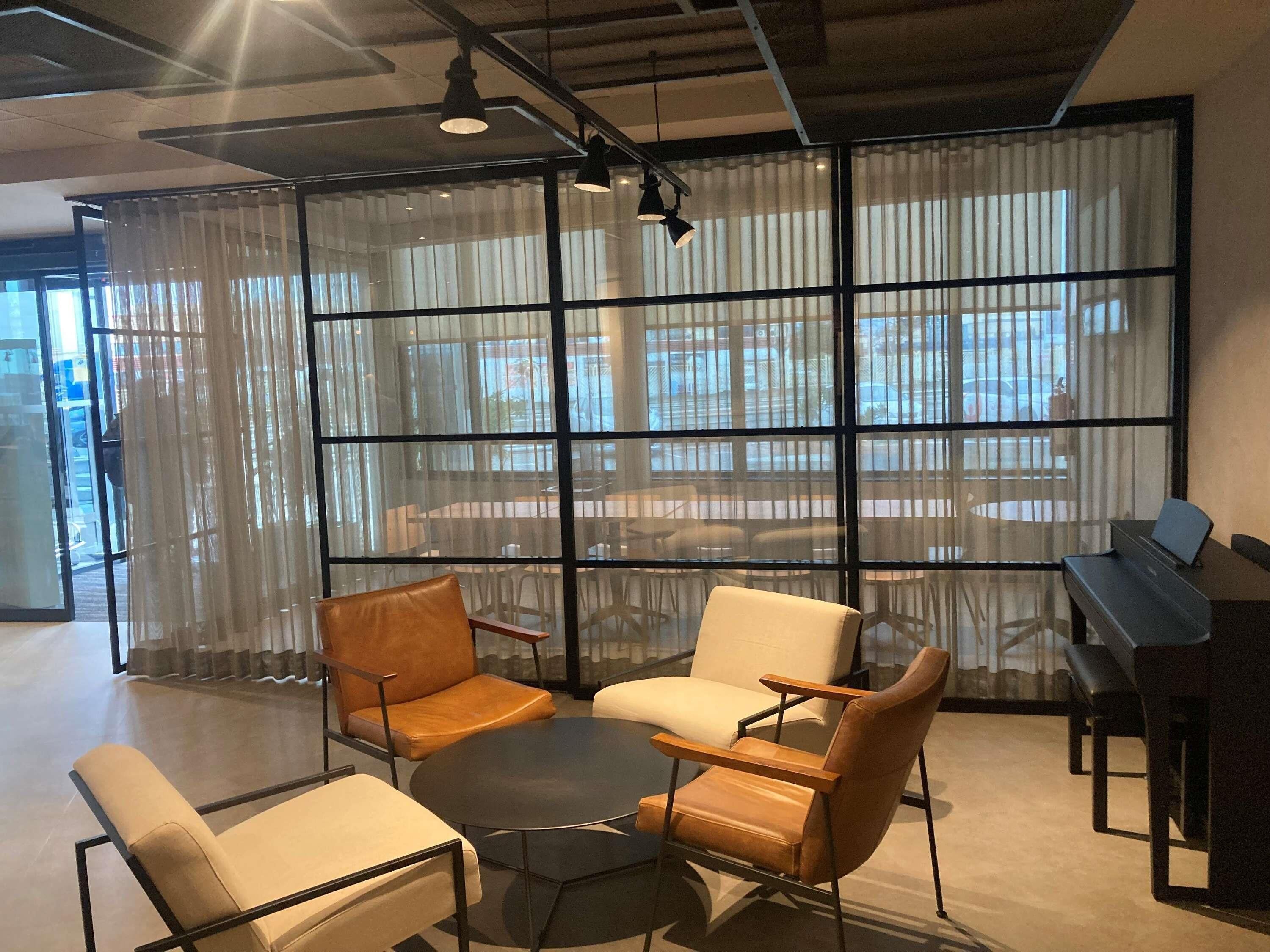 A modern meeting room with leather chairs, a round table, and a piano.