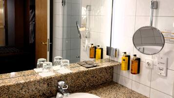 A modern bathroom with a granite countertop, a sink, a mirror, and a shower area.