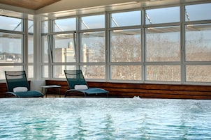 Una piscina techada, una piscina al aire libre, sombrillas