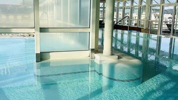 Een binnenzwembad, een buitenzwembad en parasols bij het zwembad