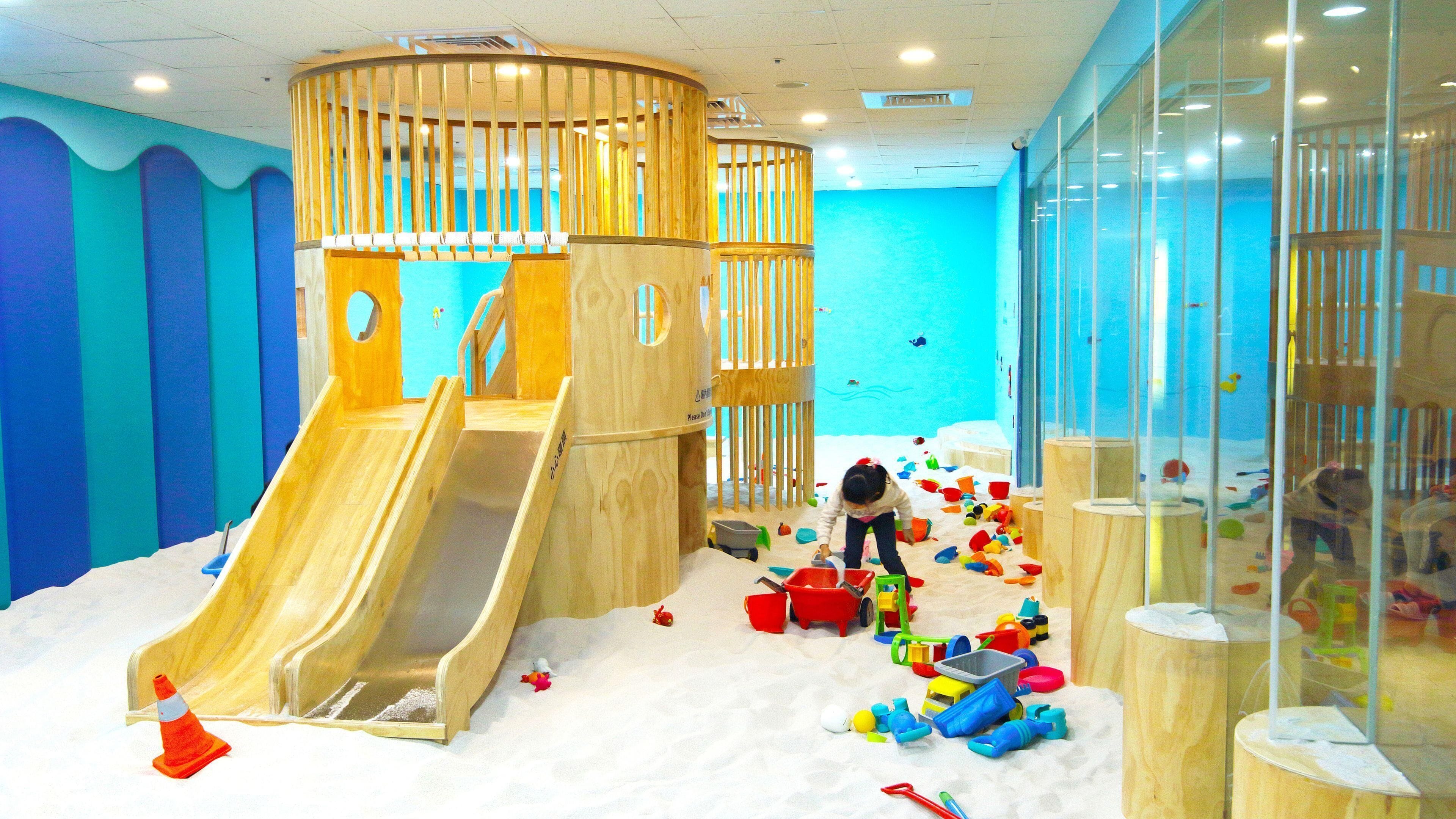 A play area with a wooden slide, sand, and various toys.