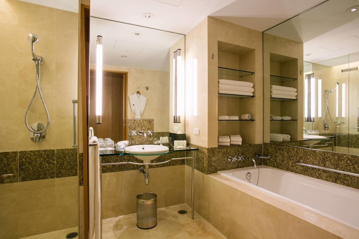 A modern bathroom with a glass-enclosed shower, a sink, a bathtub, and a mirror.