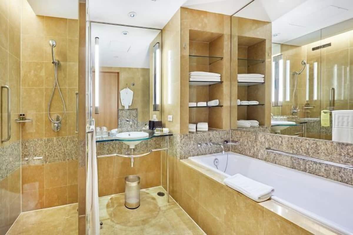 A modern bathroom with a glass-enclosed shower, a standalone bathtub, and a vanity with a glass sink.