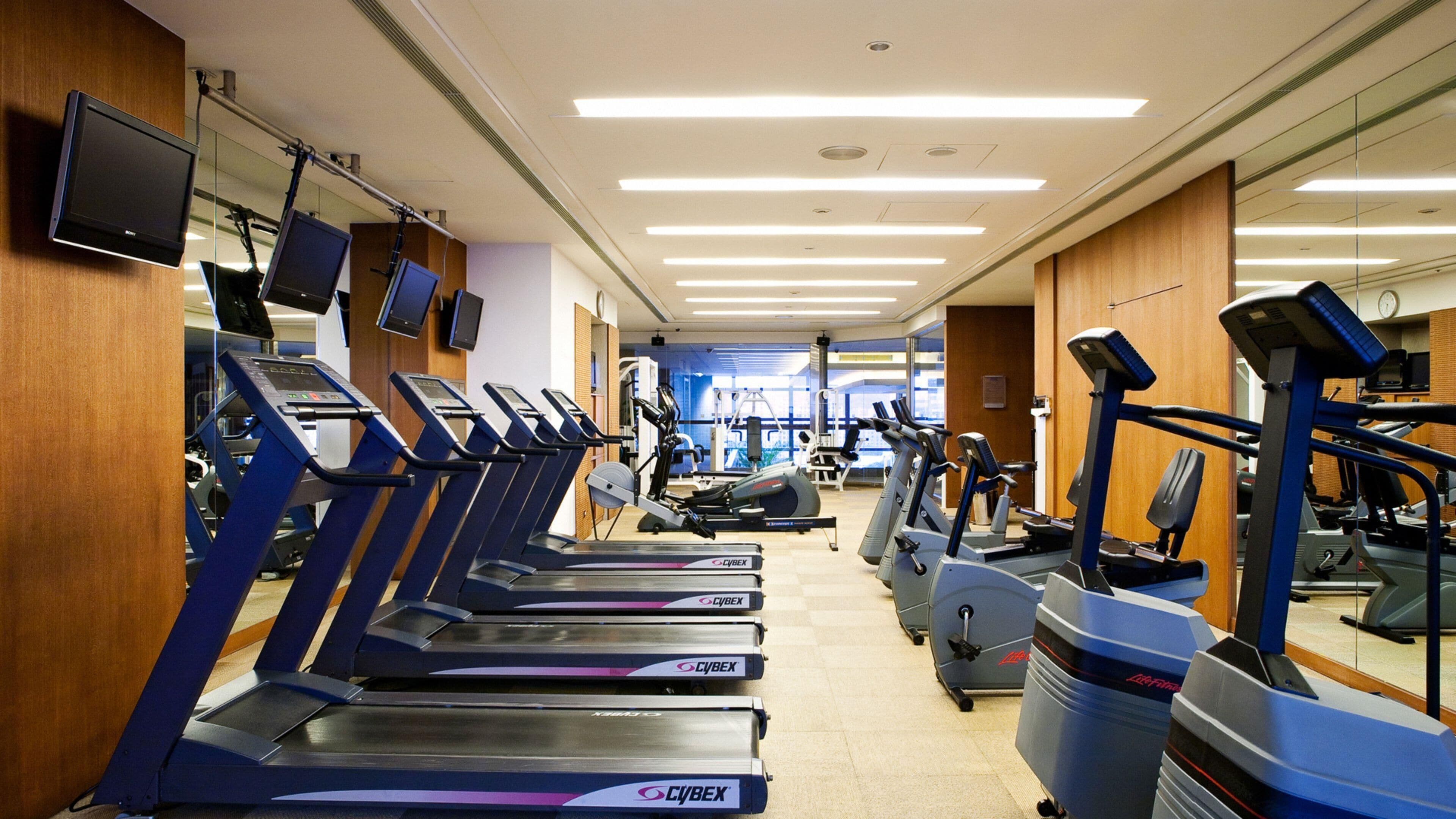 A gym with multiple treadmills, exercise bikes, and weight machines.
