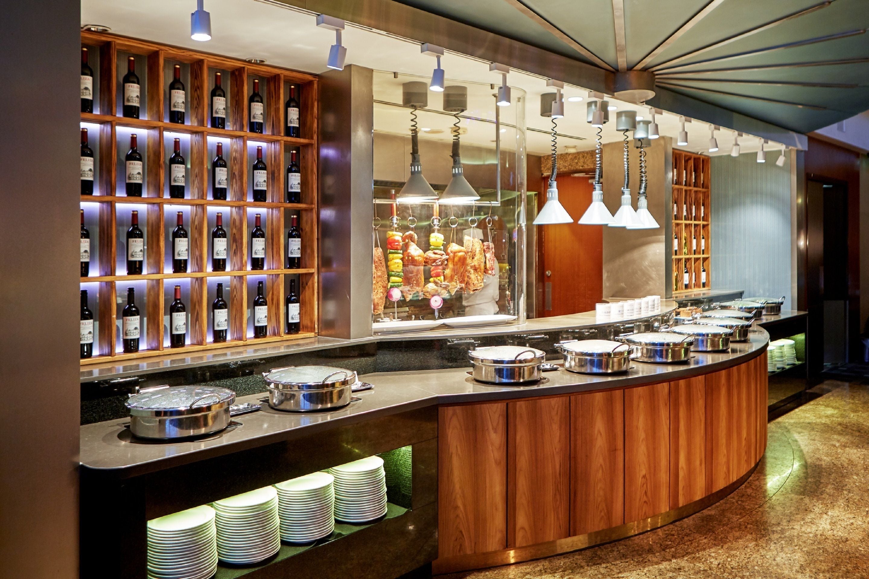 A buffet area with a wine rack, hanging lights, and a variety of food dishes.