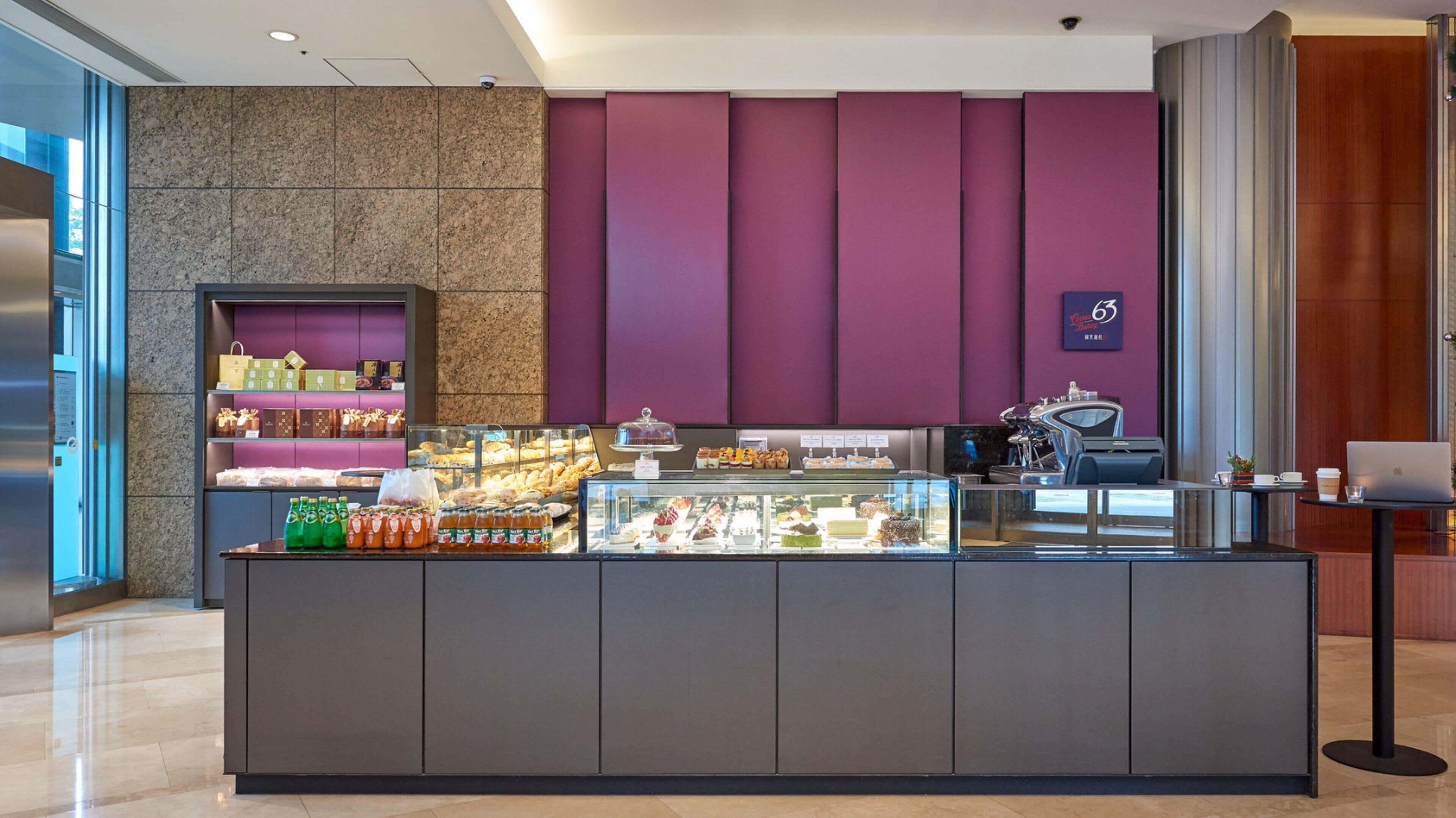 A modern cafe with a marble counter, a variety of pastries and beverages, and a coffee machine.