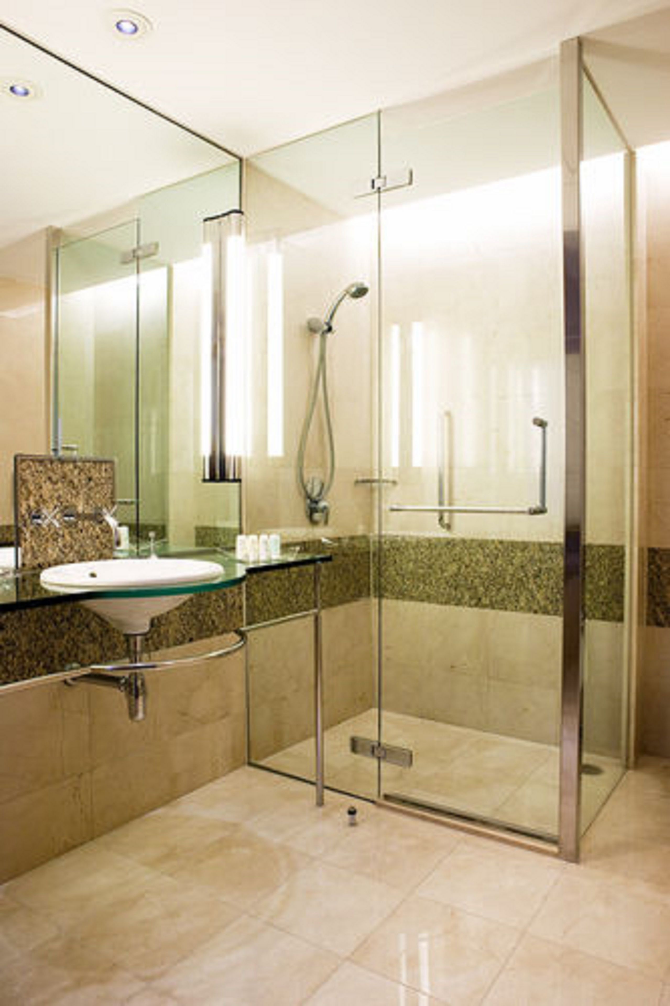 A modern bathroom with a glass-enclosed shower, a granite countertop sink, and a large mirror.
