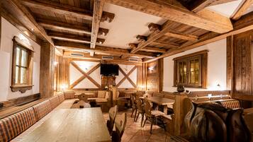 Un'area pranzo rustica con panche e tavoli di legno, un camino e un televisore.