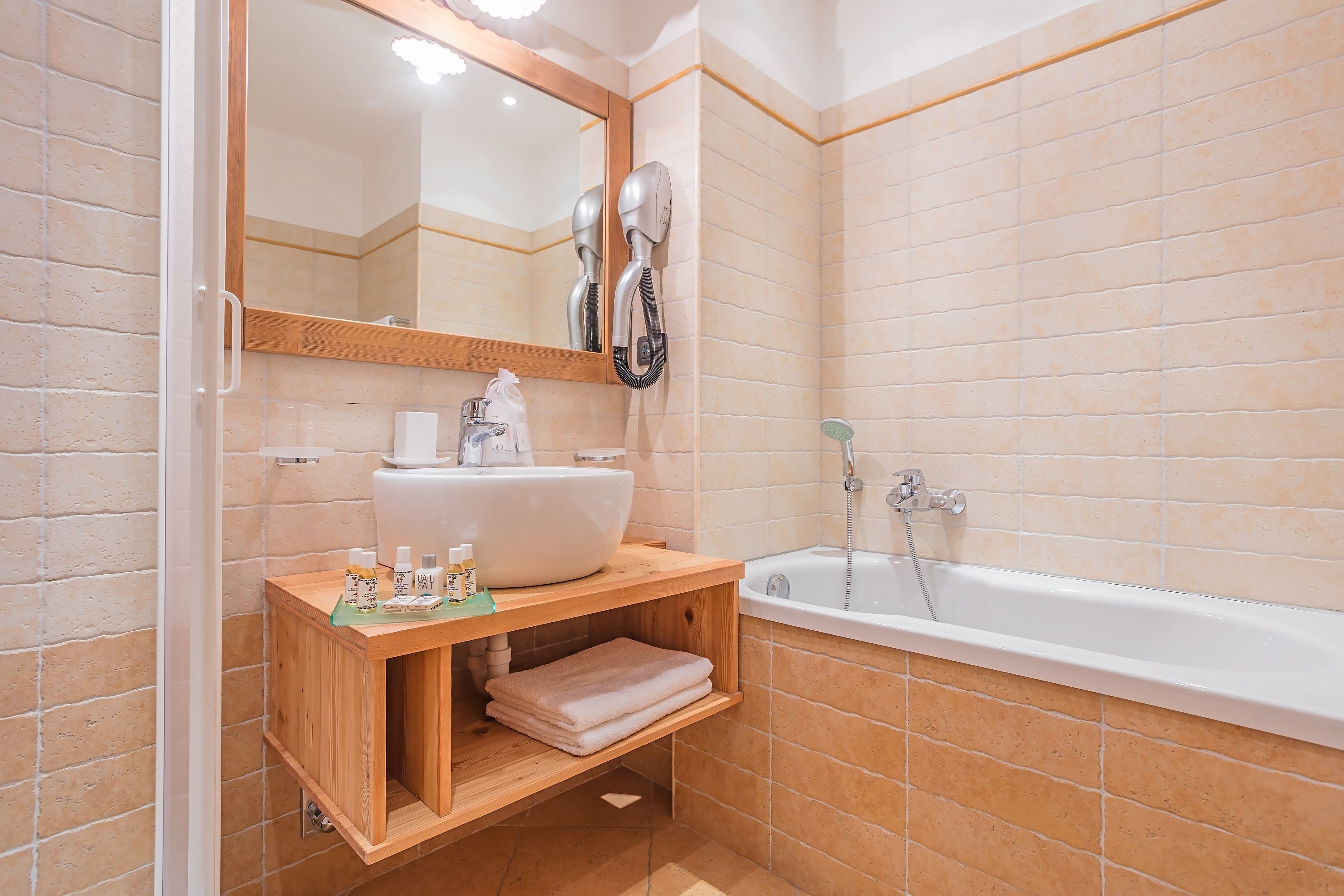 Ein Badezimmer mit einem Holzbadezimmer, einem Waschbecken, einem Spiegel, einem Fön und einer Badewanne.