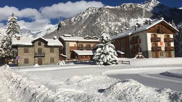 Ein mit Schnee bedecktes Berghotel mit Stein- und Holzarchitektur, eine Seilbahn und ein freier Blick auf die umliegenden Berge.