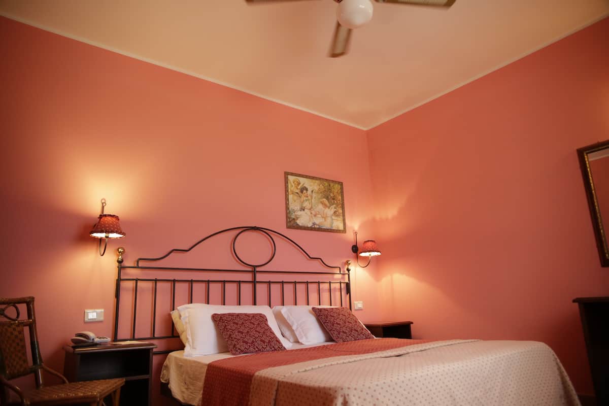 Een slaapkamer met een bed, nachtkastjes, een stoel en een plafondventilator.
