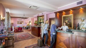 A reception area with a wooden reception desk, a large mirror, and a bar area with shelves of bottles. - I Calanchi Country Hotel & Resort (Ripatransone)