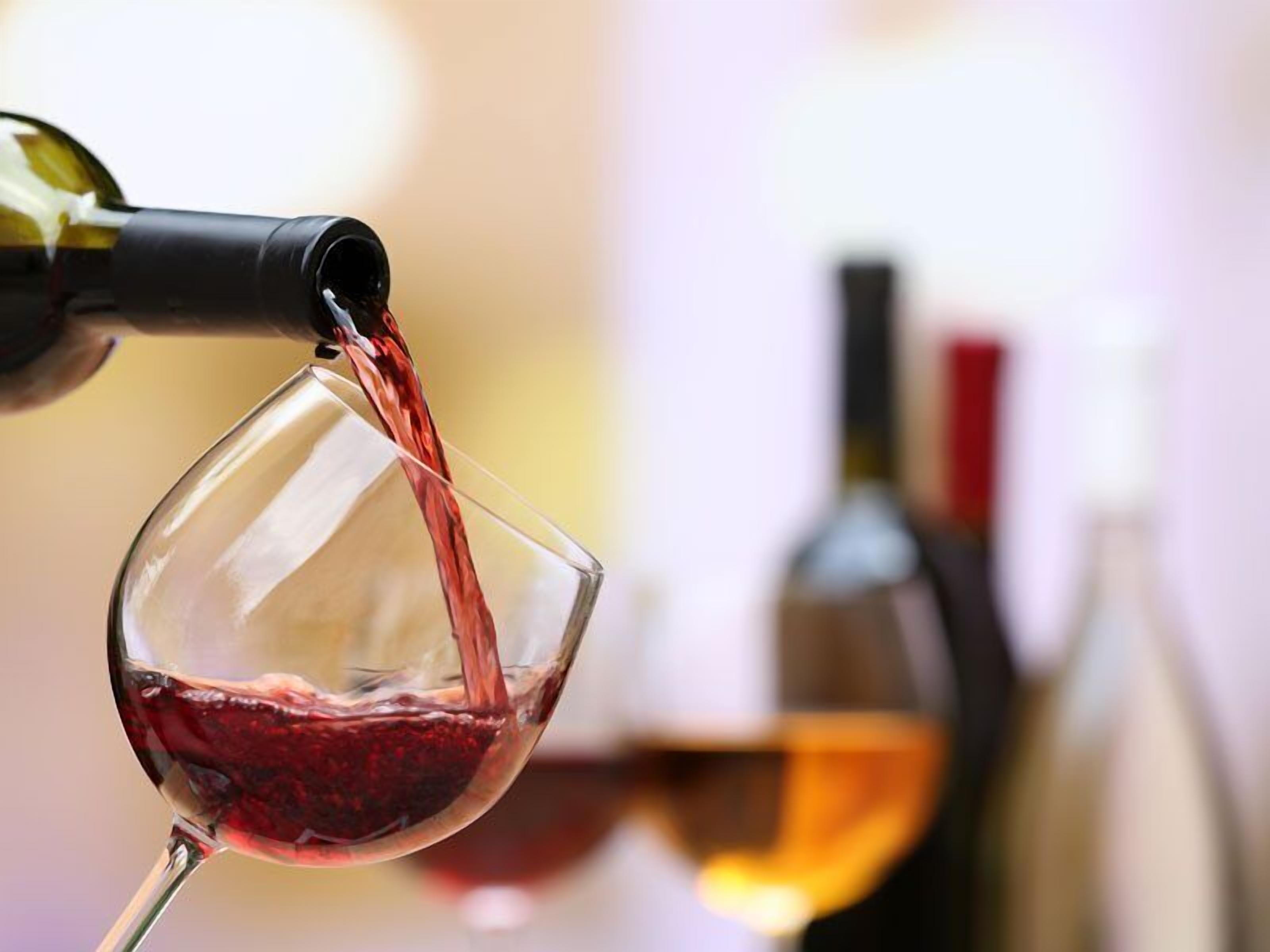 A wine glass being filled with red wine.