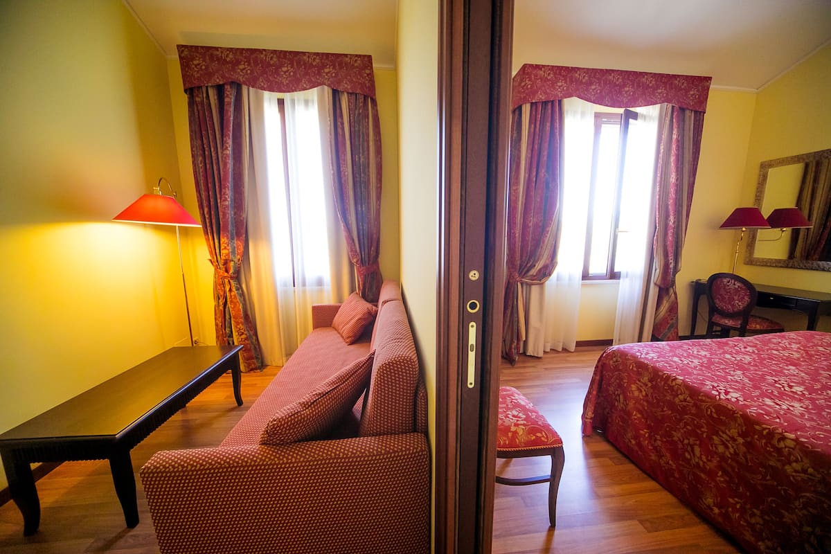Een hotelkamer met een bank, een bed, een bureau en een stoel.