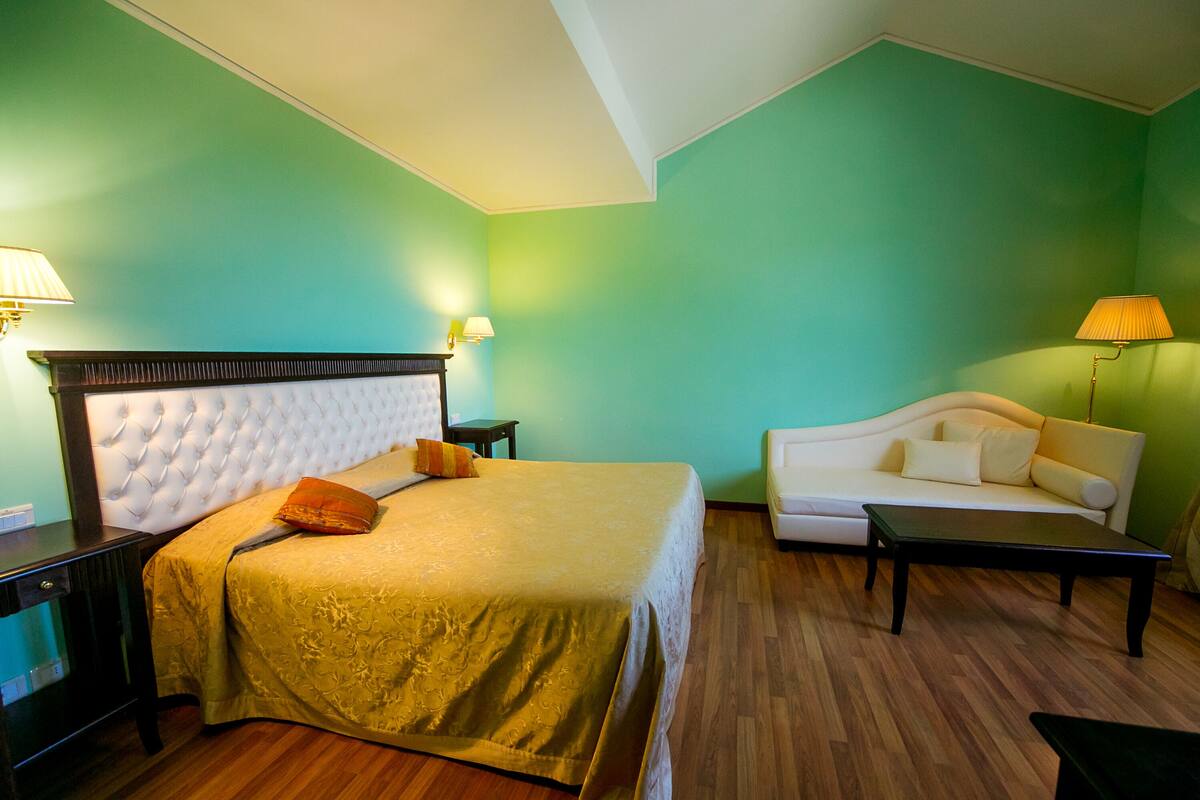 Een hotelkamer met een groot bed, een slaapbank, een bureau en een lamp.