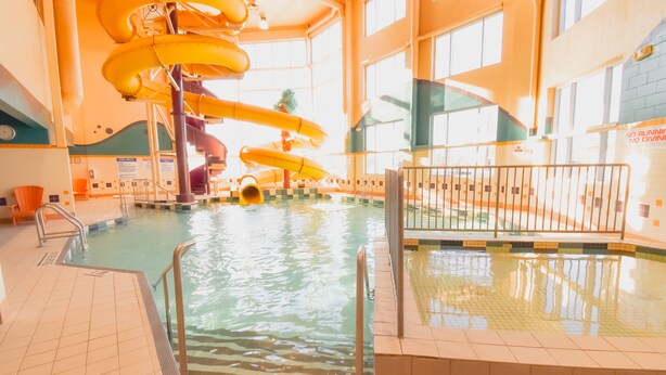 Una piscina interior con múltiples toboganes y suelo de baldosas.