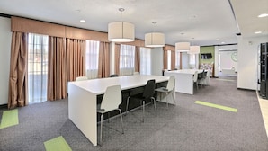 Une salle de conférence moderne, dotée d’une longue table, de plusieurs chaises et d’un système d’éclairage suspendu.