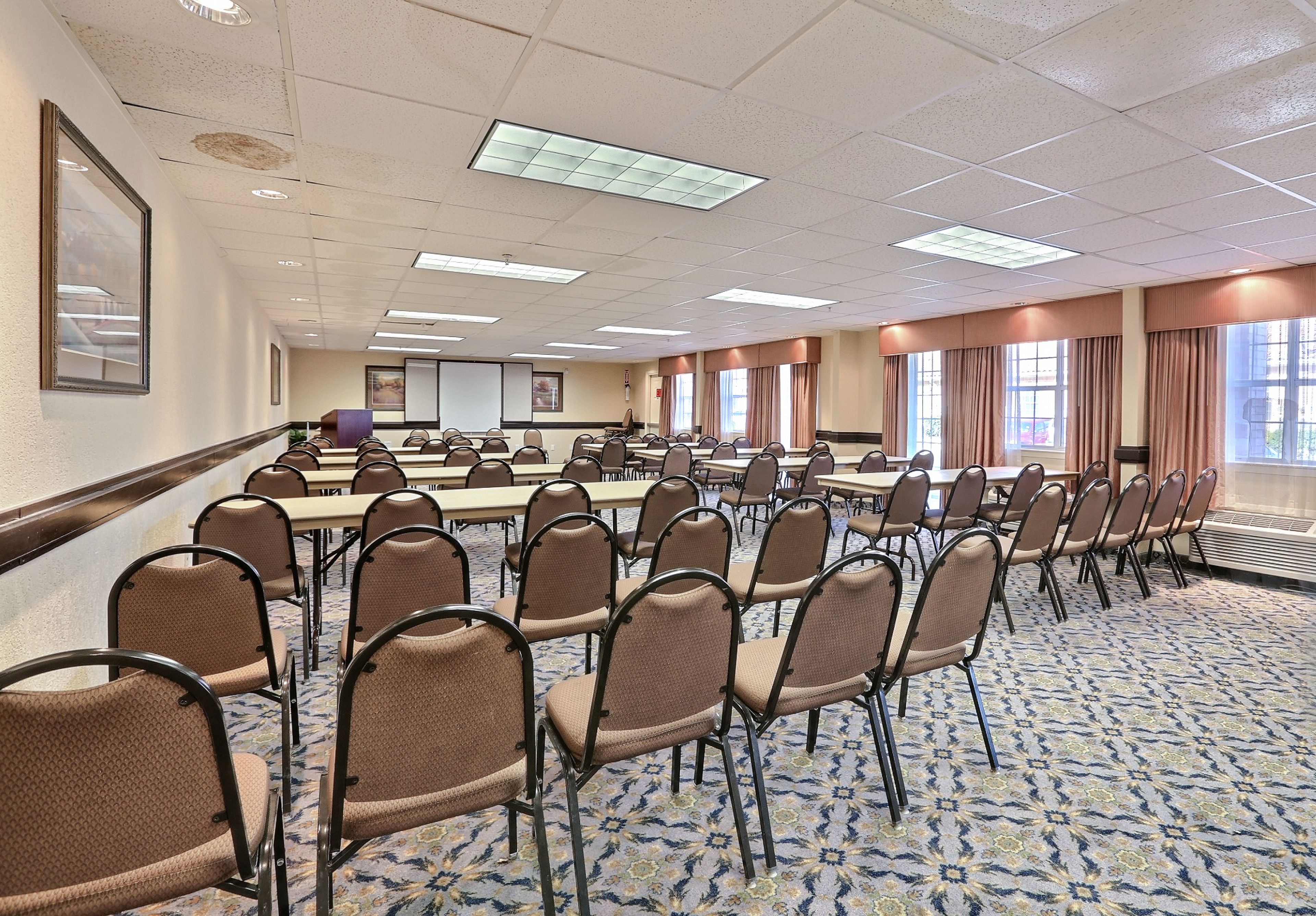 A conference room with rows of chairs, a large table, and a projector screen.