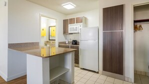 A compact kitchen with a microwave, refrigerator, and wooden cabinets.