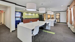 Un hall d’hôtel moderne comprenant un comptoir d’accueil, un espace salon et un panneau indiquant la présence d’un studio doté d’une connexion Wi-Fi.