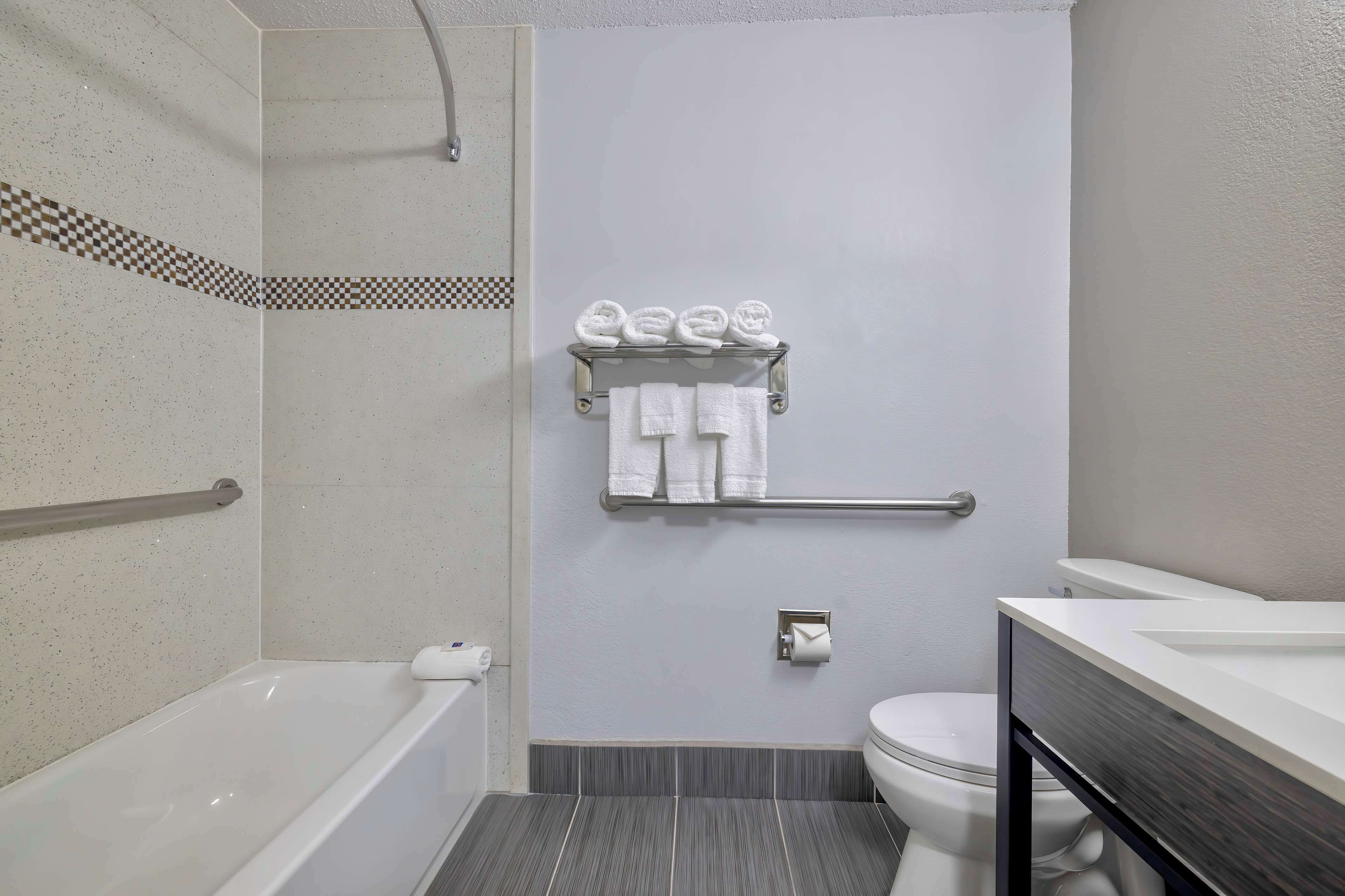 A bathroom with a bathtub, toilet, and a towel rack with towels.