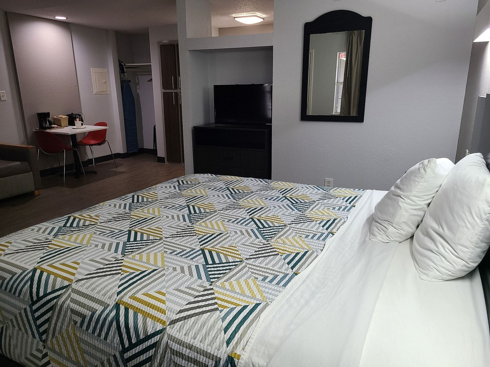 A hotel room with a bed, a desk, a chair, a television, and a mirror.