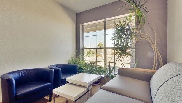 A modern living room with a blue sofa, a grey sofa, and a white coffee table. There is a large window with a view of the outside. - Studio 6 Dallas, TX - North - Richardson (Dallas)