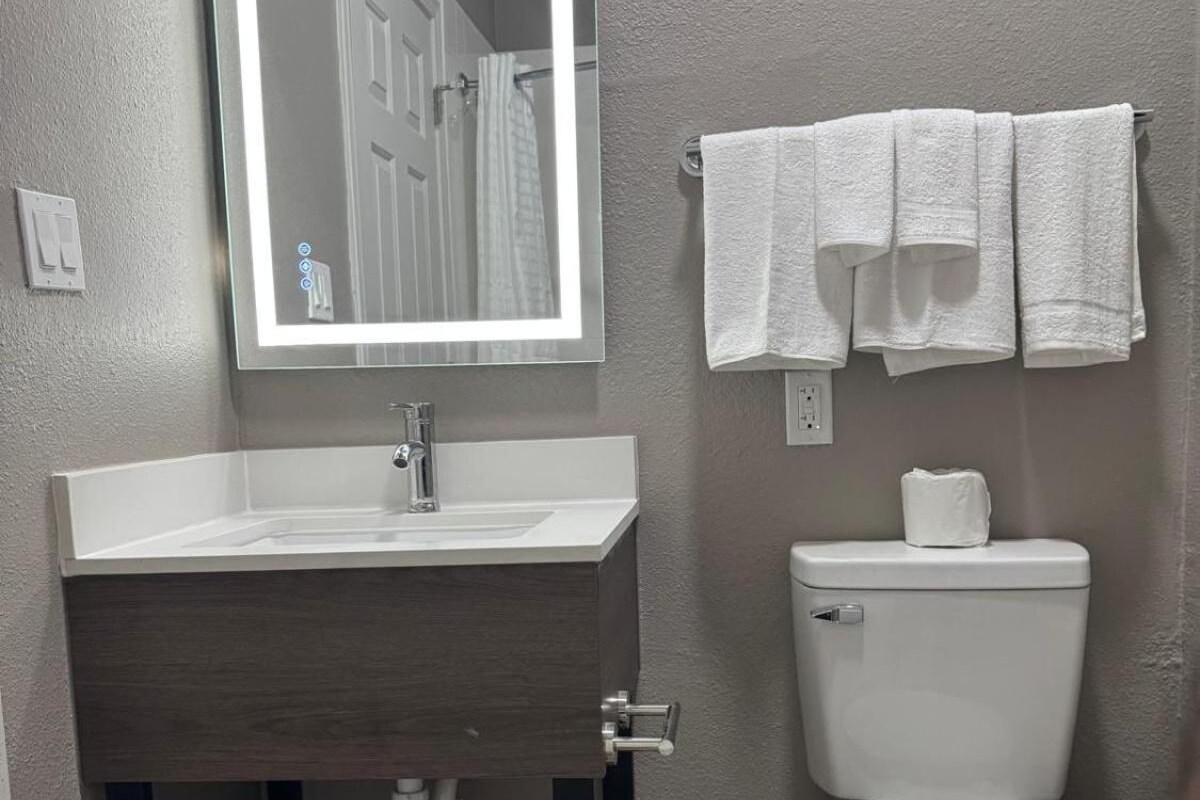 Un baño con espejo, lavabo e inodoro.