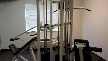 Ein Fitnessraum mit einer Smith-Maschine, Bänken und einem Spiegel.