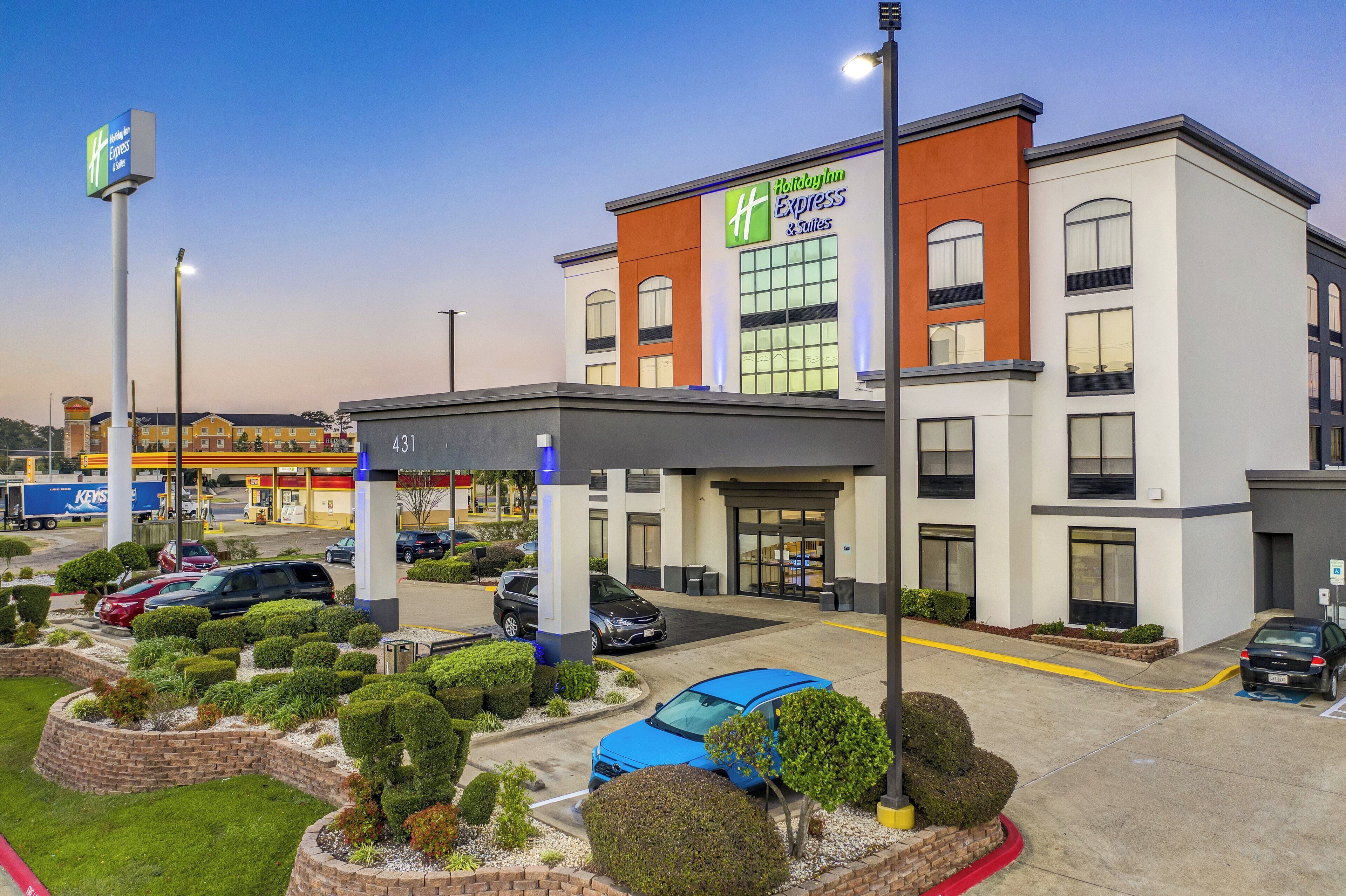 A Holiday Inn Express building with a parking lot, a gas station, and a well-maintained landscaped area.