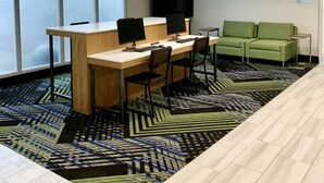 A conference room with a long table, chairs, a green sofa, and a large screen. - Holiday Inn Express & Suites Longview North by IHG (Longview)