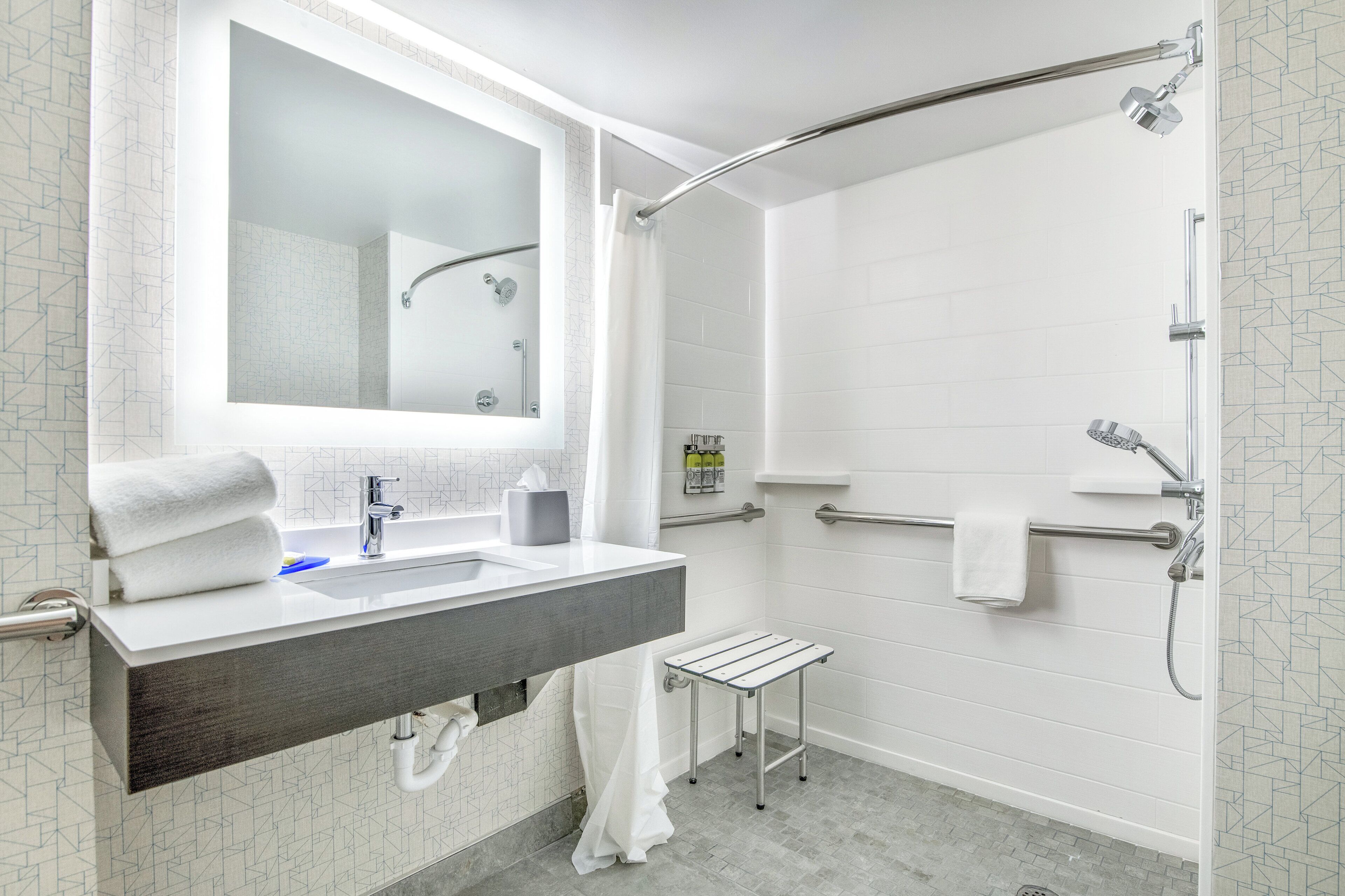 A modern bathroom with a shower, a sink with a towel rack, and a mirror.