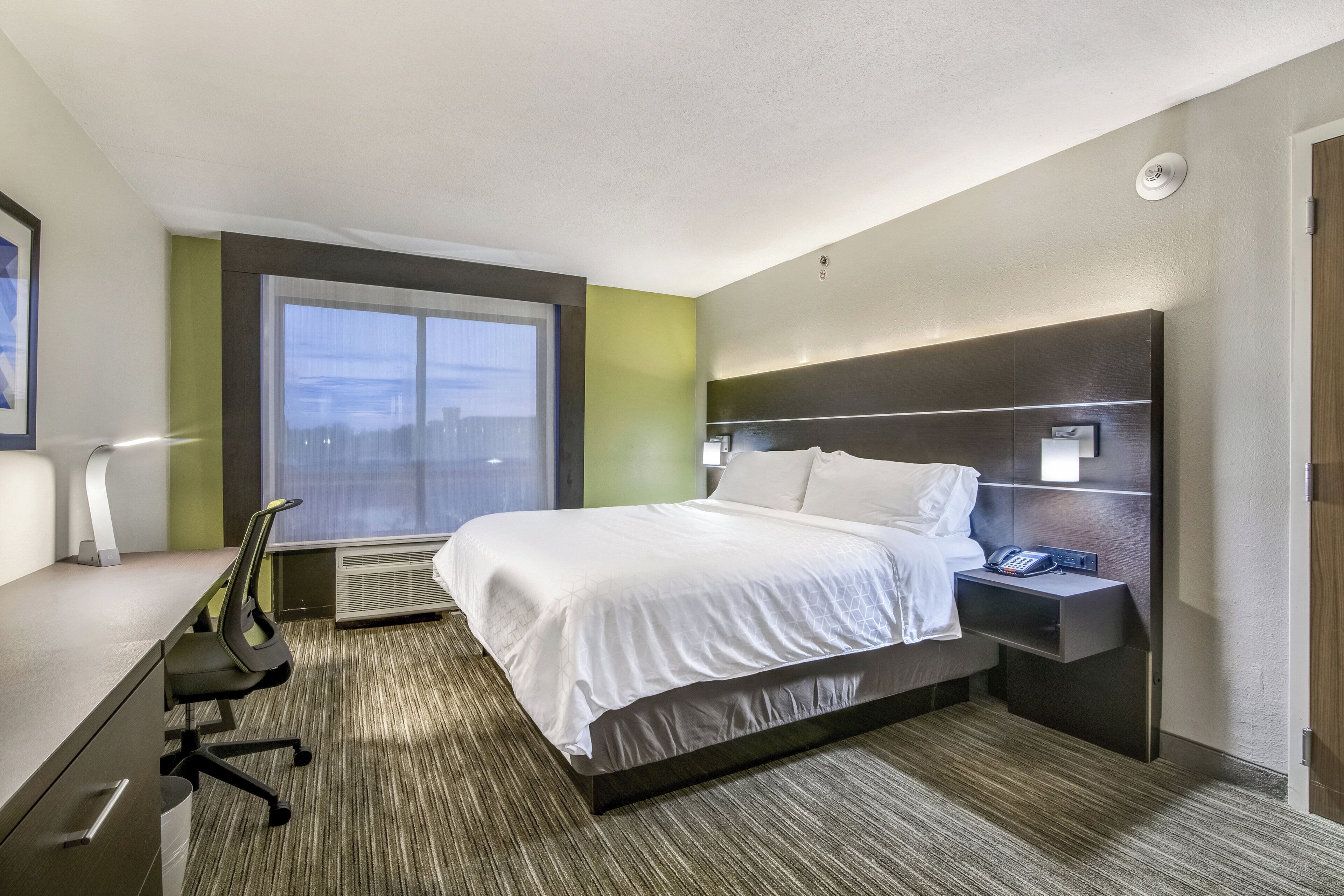 Een hotelkamer met een bed, bureau, stoel en een raam met uitzicht.