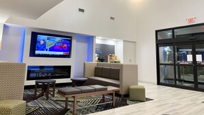 A modern lobby with a flat-screen TV displaying weather information, comfortable seating, and a fireplace. - Holiday Inn Express & Suites Longview North by IHG (Longview)