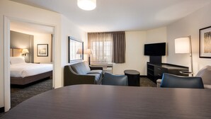 Una habitación de hotel con cama, escritorio, silla, televisión y lámpara.