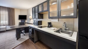 Una cocina compacta con comedor, televisor de pantalla plana, microondas, cafetera y refrigerador.