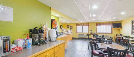 A restaurant with a counter, chairs, and tables.