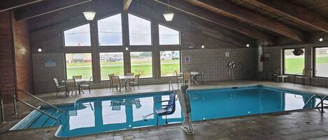 An indoor swimming pool with a high ceiling and large windows.