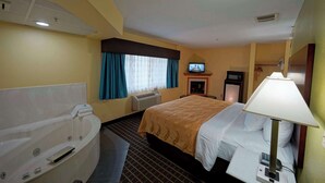 Une chambre d’hôtel avec un grand lit, une salle de bain séparée avec une baignoire, une télévision et une lampe.