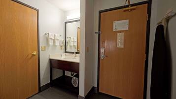 A bathroom with a wooden door, a sink, and a mirror.