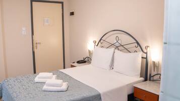 Una habitación de hotel con cama, mesita de noche y una puerta.