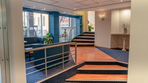 Un vestíbulo de hotel con una zona de estar azul, una escalera y un cartel que dice 'Aga Anita Hotel & Hotel'.