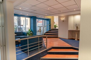 Un vestíbulo de hotel con una zona de estar azul, una escalera y un cartel que dice 'Aga Anita Hotel & Hotel'.