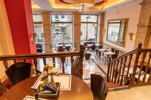 Un vestíbulo de hotel con zona de comedor, una escalera y vistas a la calle.